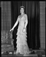 Woman modeling a lace evening gown and crown, circa 1928-1933