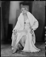 Peggy Hamilton modeling an ermine coat and silk gown accessorized with a pendant necklace, 1929