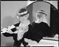 Peggy Hamilton modeling an Adrian gown with ruffles at the wrists and collar and a straw hat, 1933