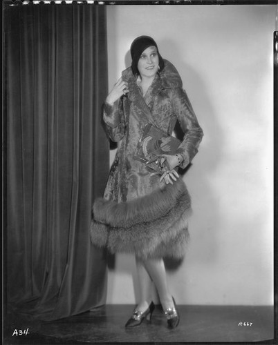 Peggy Hamilton modeling a full-length caracul coat with red fox hem, 1930