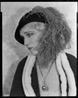 Peggy Hamilton modeling a dress or coat with light fur trim and a hat trimmed with an ostrich feather, circa 1931