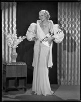 Peggy Hamilton modeling an evening gown with wide fur sleeves, 1933