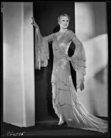 Peggy Hamilton modeling a Travis Banton hostess gown with beaded chiffon and gold lace, 1932