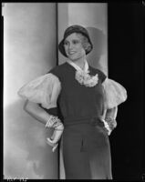 Peggy Hamilton modeling a fitted dress, a hat and embroidered gloves, circa 1931-1933