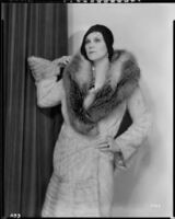 Peggy Hamilton modeling an ermine coat with red fox collar and a cloche, 1930