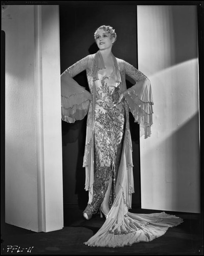 Peggy Hamilton modeling a Travis Banton hostess gown with beaded chiffon and gold lace, 1932