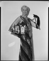 Peggy Hamilton modeling a Travis Banton gown of black net with gold palettes and sequins, 1931