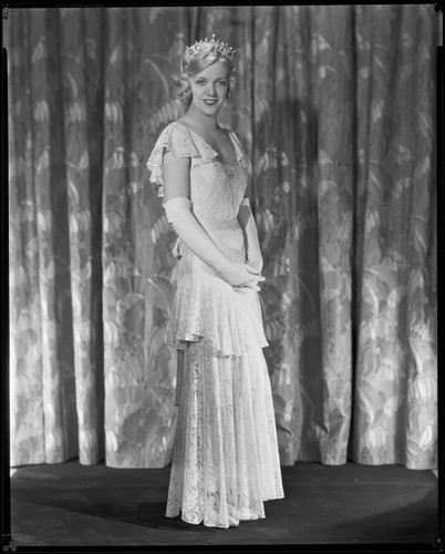 Woman wearing a lace evening gown and crown, circa 1930-1933