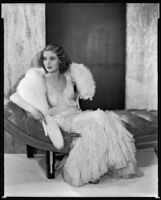 Actress Loretta Young modeling a white fox stole over a pale pink spring evening gown of ruffled net, 1931