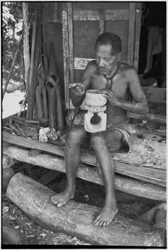 Carving: M'lapokala carving a wooden bowl with a stand, probably for tourist trade, other carvings (l)