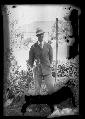 Portrait of a young man in suit and hat standing outside
