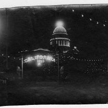 Nighttime view of the Grand Electric Carnival Admission Day, 1905 parade. This view shows the southeast corner of 10th and L Streets, note the bear emblem of the Native Sons of the Golden West in lights on the state capitol building