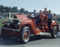 Volunteer firemen, Woman, and Child on Fire Truck, date unknown