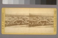 [Group of people crowded onto a two storey building]