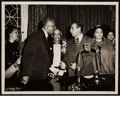 A. Philip Randolph and Vincent Impellitteri shaking hands next to (left-right) Mrs. M.P. Webster, Lucille Campbell Green, B.F. McLaurin, Bennie Smith