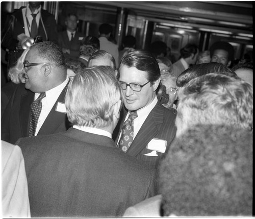 Elliot Richardson talking with others among a crowd on the Queen Mary, Los Angeles, 1972