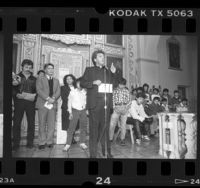 Father Richard Estrada [?] with released INS detainees at Our Lady Queen of Angels Church, Calif., 1987