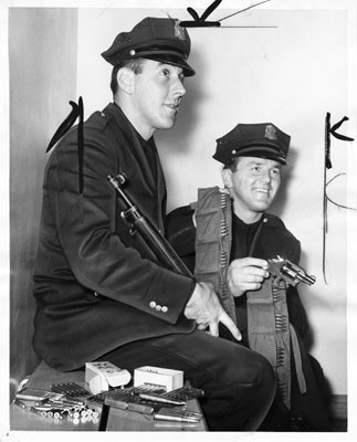 [Officers John Wydler and Paul Schneider displaying one man's arsenal]