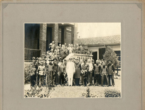 Group portrait of men in front of brick building