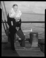Ralph D. Cornell standing on the deck of a ship wearing a suit and a stack of leis, Hawaii, 1938