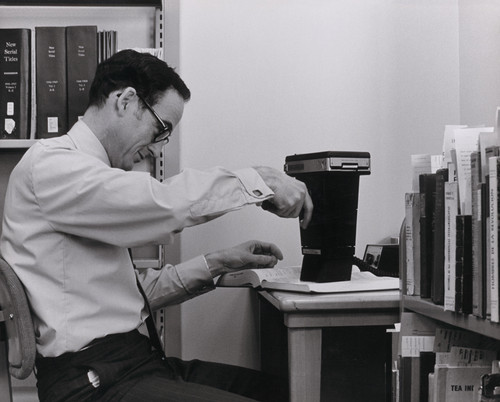A photograph of Ray Reeder with a strange photographic device processing catalog cards