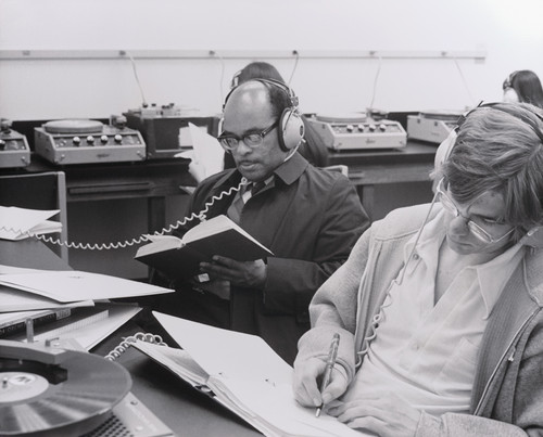 A photograph of students listening to records in one of the listening rooms located in the Upper Mall