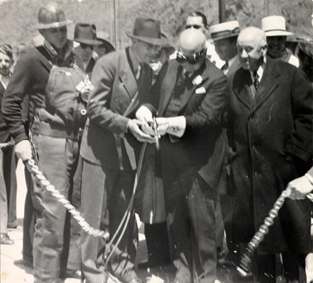 [Governor Frank F. Merriam and Mayor Angelo Rossi cutting through a chain at the San Francisco-Marin County line on the Golden Gate Bridge during opening day ceremonies for the bridge]