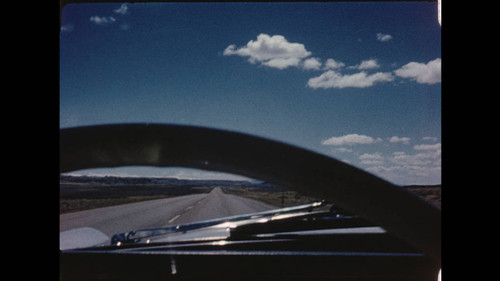 Maynard Parker Home Movie: April 2 - May 10, 1961. View of the road and sky through steering well of moving vehicle. Reel2_02.09.33.00