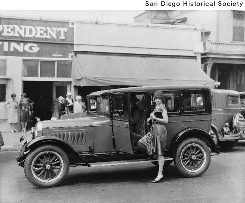 A woman with one foot resting on the running board of a 1927 Overland Whippet