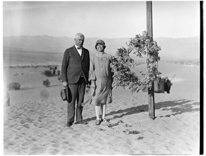 Couple standing next to a cross at a funeral in the desert