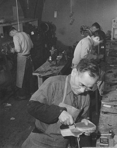 [Shoemakers at work in shoe repair shop at Heart Mountain incarceration camp]