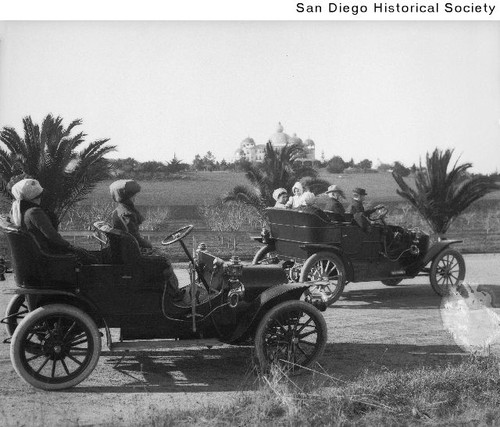 Two groups riding in a Buick and a Stanley automobiles near the Theosophical Institute