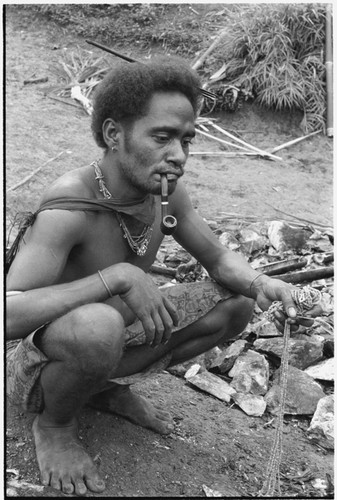 Man kneeling on ground with hand full of kofu shell money