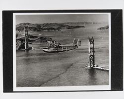 China clipper over south tower of Golden Gate Bridge first westbound flight, November 22, 1935