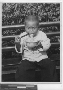 A boy eating spaghetti at Luoding, China, 1934