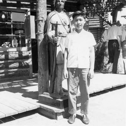 Henry Quan standing in front of a Native American statue in Disneyland
