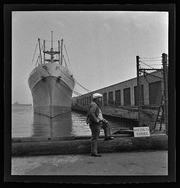 Man in front of ship at dock, California Labor School