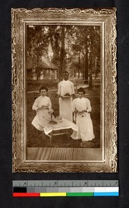 Two missionary women being served tea outdoors by an indigenous woman, Angola, ca.1914