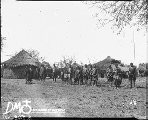African people standing in front of a village, Kouroulene, South Africa, ca. 1896-1911