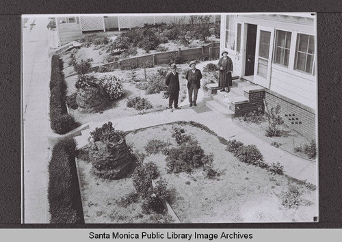Three people standing on the steps and walk of a house on Second Street near Colorado Avenue, Santa Monica, Calif