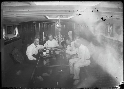 Group playing cards in cabin of Wave (yacht). [negative]
