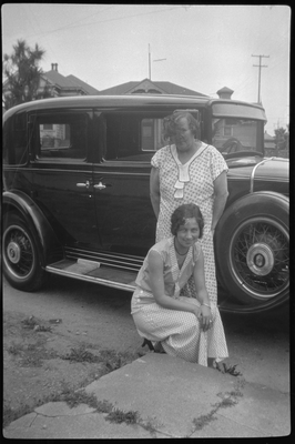 Two women standing next to automobile