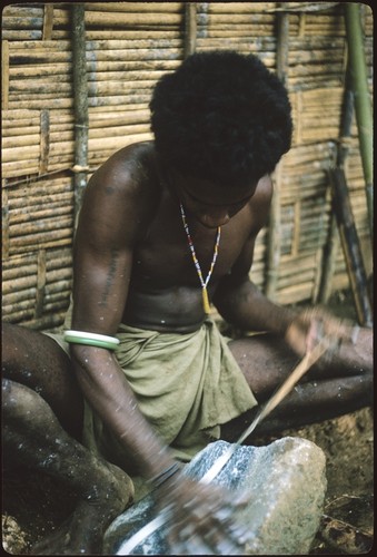 Man grinding shell money beads strung on special fiber