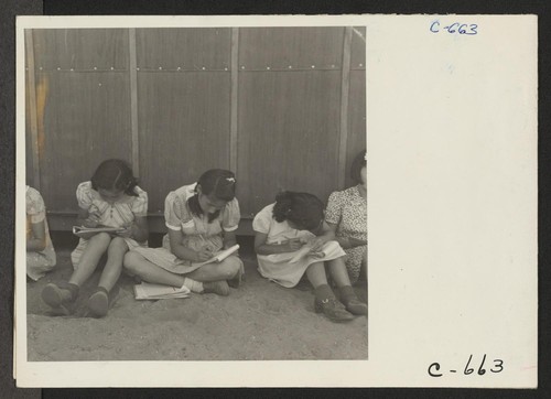 An elementary school has been established with evacuee volunteer teachers, most of whom are college graduates. Attendance at this time is voluntary. No school equipment is as yet available and classes are also held outside the barrack building in the shade. Photographer: Lange, Dorothea Manzanar, California