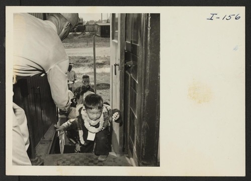 Closing of the Jerome Center, Denson, Arkansas. Travel is just another adventure to the children of the relocation centers. Here a little tot eagerly mounts the steps of the chair car assisted by a member of the military police. Photographer: Iwasaki, Hikaru Denson, Arkansas