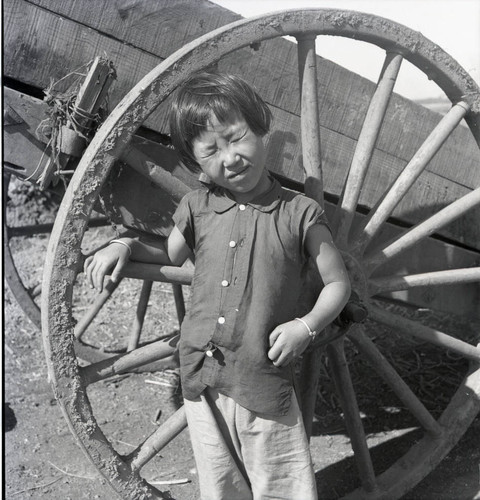 Girl with closed eyes posing with wagon wheel