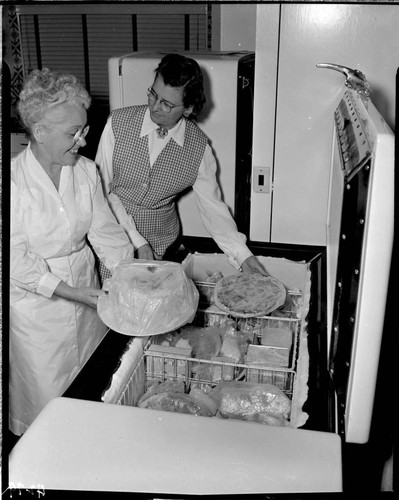 Two ladies taking food out of a deep freezer
