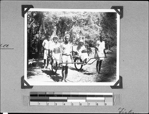 Sisters Anna and Tietzen sitting on a bush cart, Mbozi, Tanzania, 1936