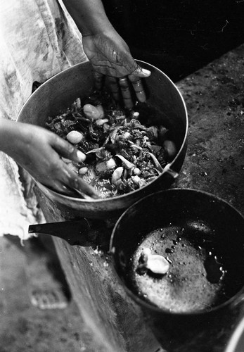 A woman stands in front of two pots preparing a meal, San Basilio de Palenque, 1977