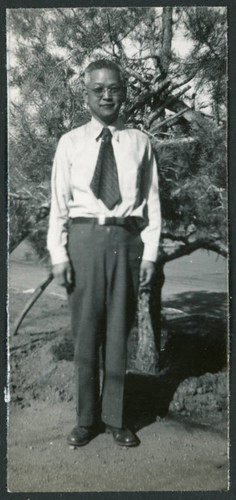 Photograph of a man posing in front of a tree at Manzanar